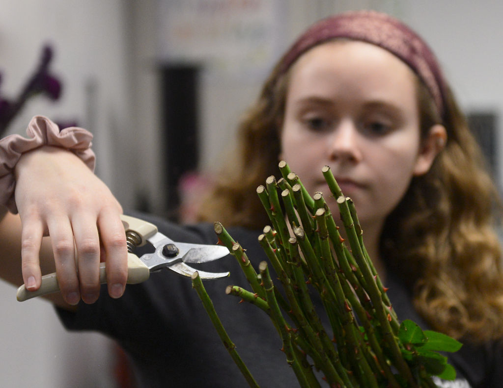 Keller Shemwell trims the stems off a bunch of flowers